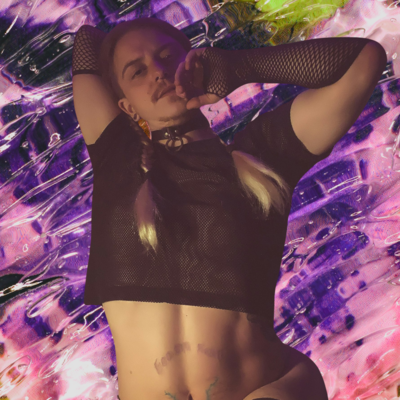 FoxFux poses with his arms up as his robe falls off him. He wears a black mesh crop top and fishnet glove with two long red to blond braids framing his face. He looks down at the viewer with his hand near his mouth. Behind him is a trippy water and ice graphic in bright purples, pinks and green. Fox wears a black collar and matching garter on his thigh.