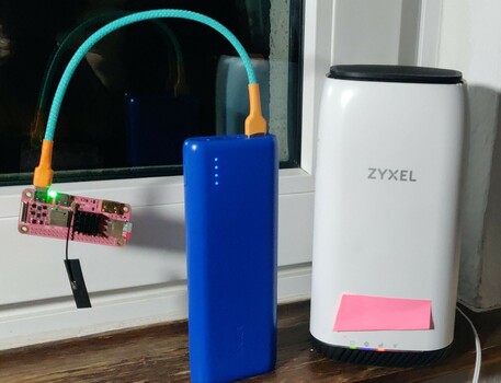 a small pink mango pi riscv sbc dangling from a recable.eu directly running from a power bank right next to a zyxel 5g router having a reachable ip.