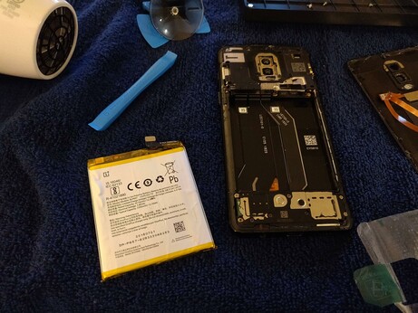 The old battery has been removed from the phone by pulling on a tab that was attached to the battery.  The tab peeled off of the battery and is visible to the right of the phone.  Unfortunately, the tab ripped apart while attaching it to the new battery, but the adhesive in the phone was also weakened so I don't think it's still needed.