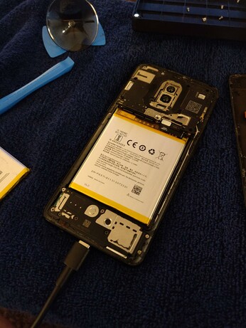 The new battery is installed in the phone, with the back cover still removed.