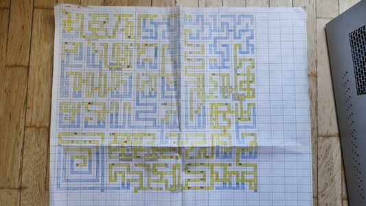 A hand-drawn map of the maze from the C64 game Hero of the Golden Talisman. It's drawn on four pieces of squared paper glued together. The corridors are colored with yellow and blue pencil — blue for the underwater sections, yellow for the regular passageways.