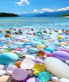Beautiful multi Colorful rounded stones fill the shore and the ocean is in the background as well as mountains in the distance