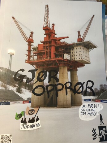 A picture of a skiing infrastructure with an oil platform photoshopped in the middle.
In the picture there is also a group of people and a single person on the side.
On the group have been drawn XR flags and a banner with written "utfasing nå", while on the single person has been written a comics bubble saying "å fæn!! Da blir jeg med!.
In the middle of the picture has been written in black "gjør opprør"